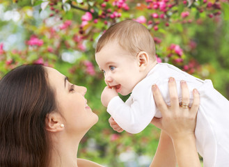 family and motherhood concept - happy smiling young mother with little baby over natural spring...