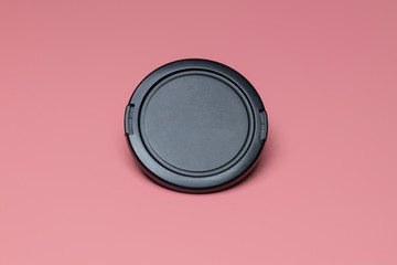 Cap from the camera lens on a pink background. Close-up.