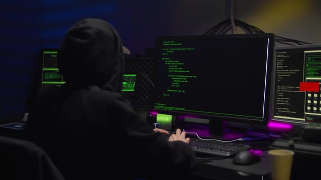 female hacker in dark room creating code for cyber attack