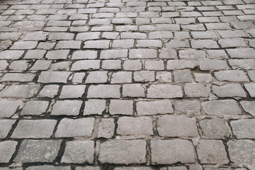 The gray paving stones close up. The texture of the old dark stone. Vintage, grunge. Road surface.