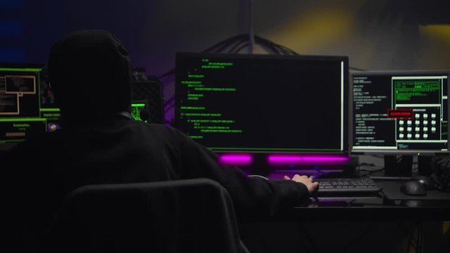 Young Hacker Girl in dark hood Attacks Servers in dark room