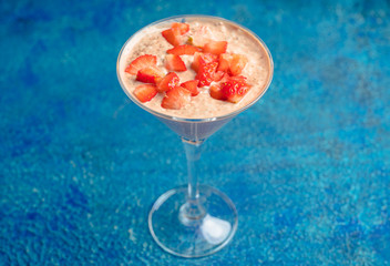 Chocolate yogurt with chia seeds and strawberry in martini glass on the rustic wooden background. Selective focus.