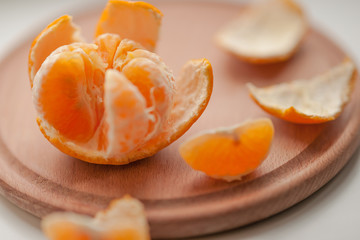 Orange mandarin with slices and peel on a wooden board.