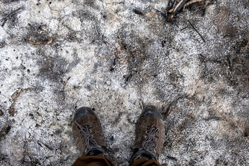 Man in trekking boots on the dried lake surface. Trekking boots on the dried saline soil surface.