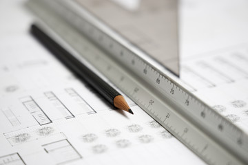 Close up of architect scale ruler, a pencil and building blueprint on worktable