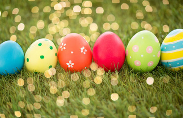 easter, holidays and tradition concept - row of colored eggs on artificial grass