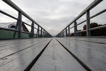 Fototapeta premium Wooden pedestrian bridge in perspective over roof of Peter and Paul fortress with cloudy sky background.