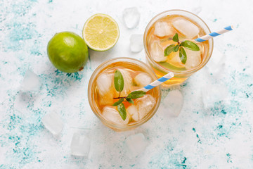 Iced tea with lime and ice on light background