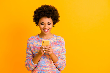 Portrait of positive cheerful afro american girl use smartphone read social network news share blogging post wear stylish clothing isolated over bright shine color background