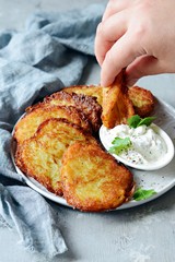 Crispy potato pancakes with green salad and yogurt sauce. Stack of potato fritters