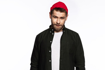Handsome man wearing red woolen hat looking at camera seriously . 