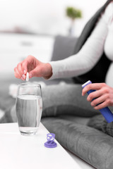 Pregnant woman taking vitamin tablet in a glass of water.