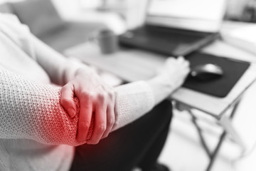 Woman working on a laptop and having elbow pain.