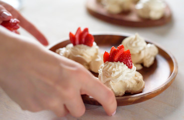 the process of creating Pavlova dessert, decorating the meringue with strawberries