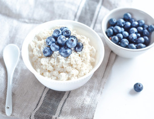 cottage cheese with blueberries on a white plate in a white bowl top view