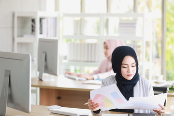 beautiful Muslim woman was sitting intently at the computer screen in the office with another colleague.