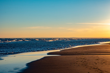 Wet sand on the coast at low tide wit clear blue sky and sea on a background.