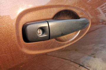 Scratched nails in the brown car door handle.