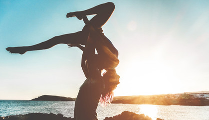 Silhouette young couple doing acroyoga outdoor on the beach - Woman and man training on evening...