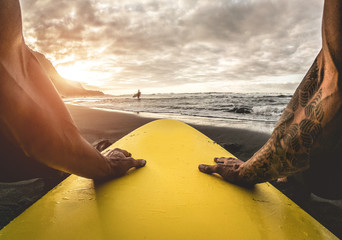 Pov view of tattoo surfer waiting waves on tropical beach - Fit atlhete having fun doing extreme water sports - Travel and healthy lifestyle concept - Focus on hands - obrazy, fototapety, plakaty