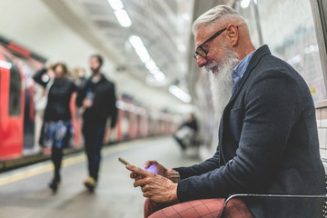 Senior hipster man using smartphone in subway underground - Fashion mature person having fun with...