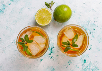 Iced tea with lime and ice on light background