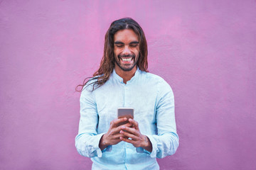 Fototapeta Handsome man in casual clothes  using a smartphone app with purple wall in background - Focus on his face obraz