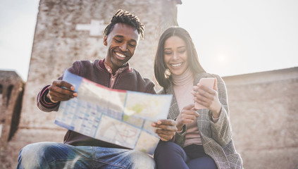 African couple looking city map during vacation tour - Happy young people having fun in down town center - Travel, love and wanderlust concept - Main focus on man face
