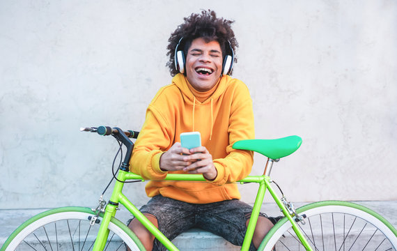 Happy african millennial guy listening music playlist with smartphone app outdoor - Young man having fun with technology trends - Tech, generation z and stylish concept - Focus on face