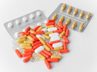 Medicine pills on white background, close-up. Blisters with pills and scattering of colorful tablets	