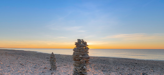 Empilement de galets sur une plage au coucher de soleil, ambiance zen.
