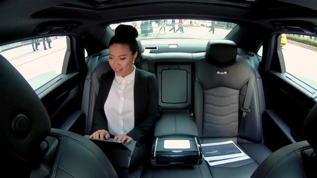 Time lapse video of positive chinese female executive manager checking information making proofread of documentation while sitting on back seats of car