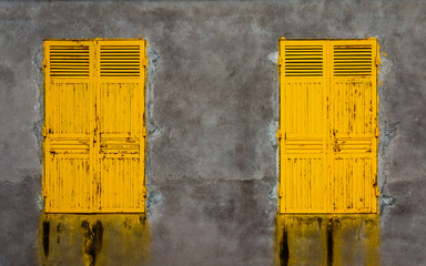 Two bright yellow colored wooden doors in a grey stone wall