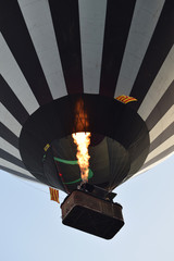 Un globo aerostático despegando y volando arriba con una gran llama de fuego