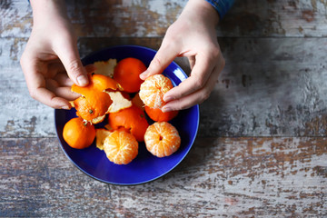Men's hands are peeling mandarin. Tangerines on a plate. Skins of tangerine.