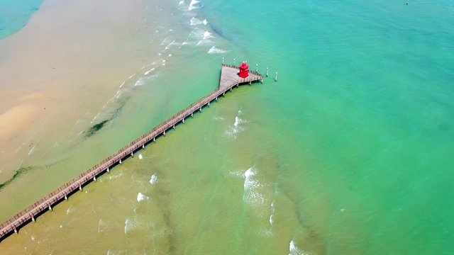 Aerial shot of Faro Rosso, a red lighthouse at the end of a pier in Lignano Sabbiadoro, Italy