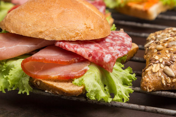 Grilled sandwich with  bacon, salami, cheese and salad on metal grill