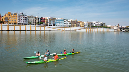Views of Guadalquivir River with several tourists enjoying canoeing downstream, popular water sport...