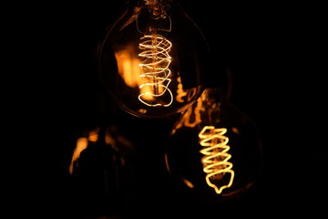 Classic Edisson bulbs backgound. Retro style bulbs. Vintage glowing light bulbs on a black...