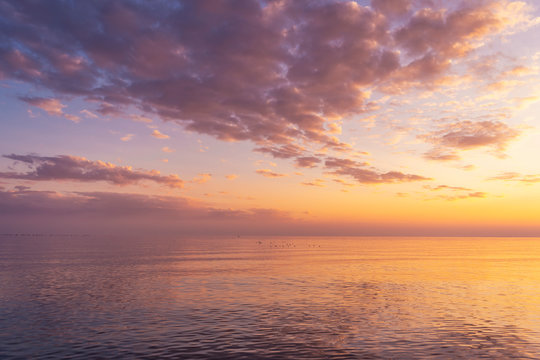 Beautiful sunset over sea with reflection in water, majestic clouds in the sky