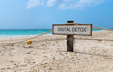 Old wooden sign with text digital detox on tropical beach