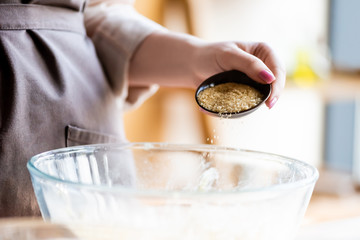 cropped view of woman adding brown sugar in bowl