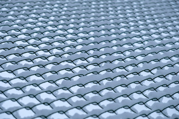 Metal mesh covered with snow. Metallic grid with snow background.