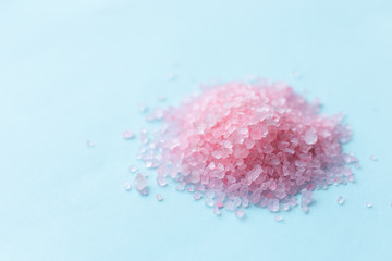 heap of large sprinkled crystals of pink sea salt closeup on a blue background with place for text. body care concept
