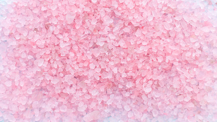 heap of large sprinkled crystals of pink sea salt closeup on a blue background with place for text. body care concept