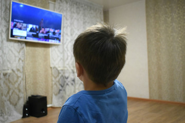 the boy watches TV at home