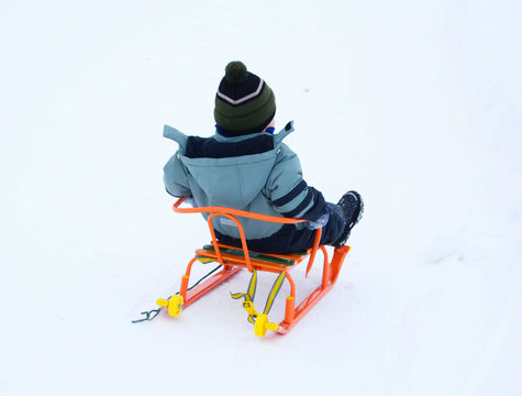 a child on a sled rides down a hill