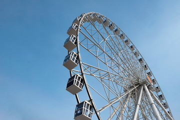 Modern ferris wheel on a blue sky background. Huge ferris wheel with cabins.