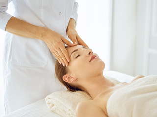 Beautiful woman enjoying facial massage with closed eyes. Spa treatment concept in medicine