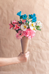 Hand hold bouquet of flowers. Unrecognizable woman hands holding a beautiful bouquet of colorful spring flowers against crafty brown paper background